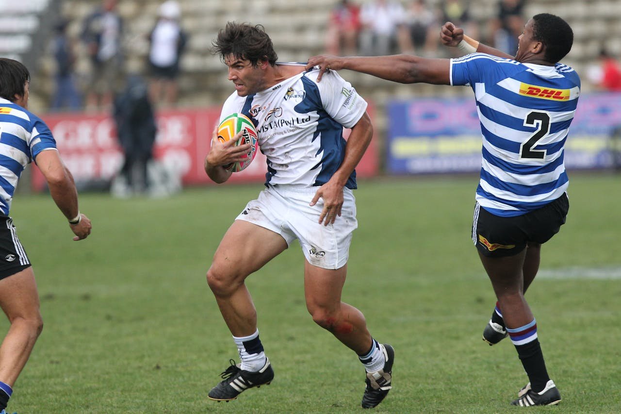 about-us Rugby players in motion during a competitive game on a grassy field.